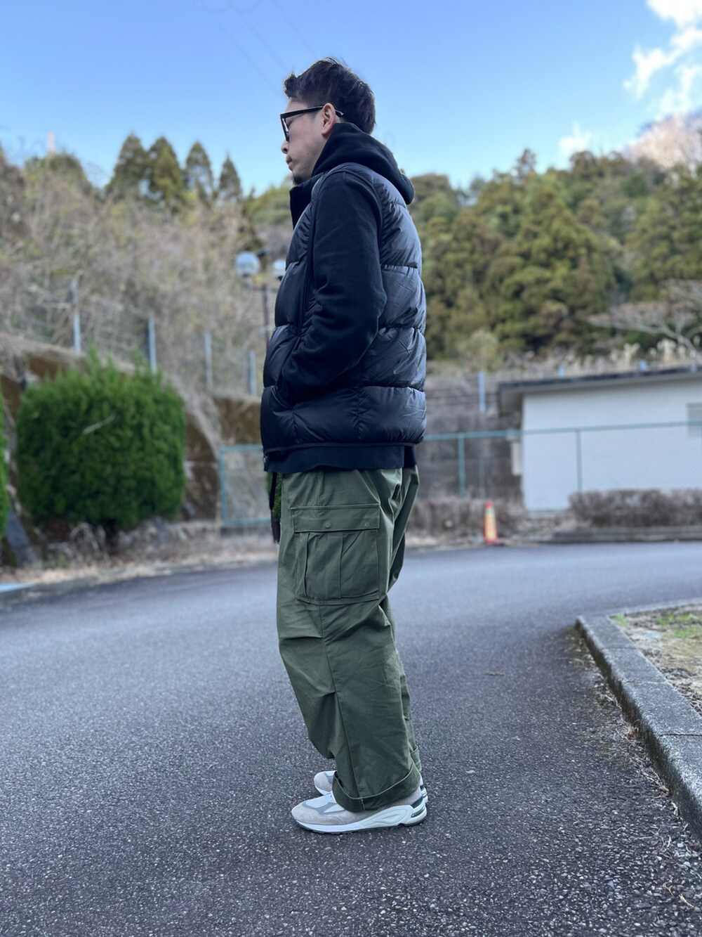 ブラック系のダウンベスト、グリーン系のカーゴパンツ、グレー系のスニーカーを着用したメンズの冬コーディネートの2枚目の写真