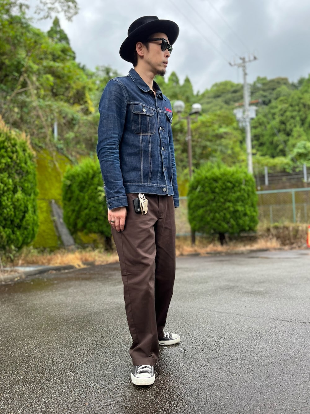 ブルー系のデニムジャケット、ブラウン系のチノパンツ、ブラック系のスニーカーを着用したメンズの秋コーディネートの2枚目の写真