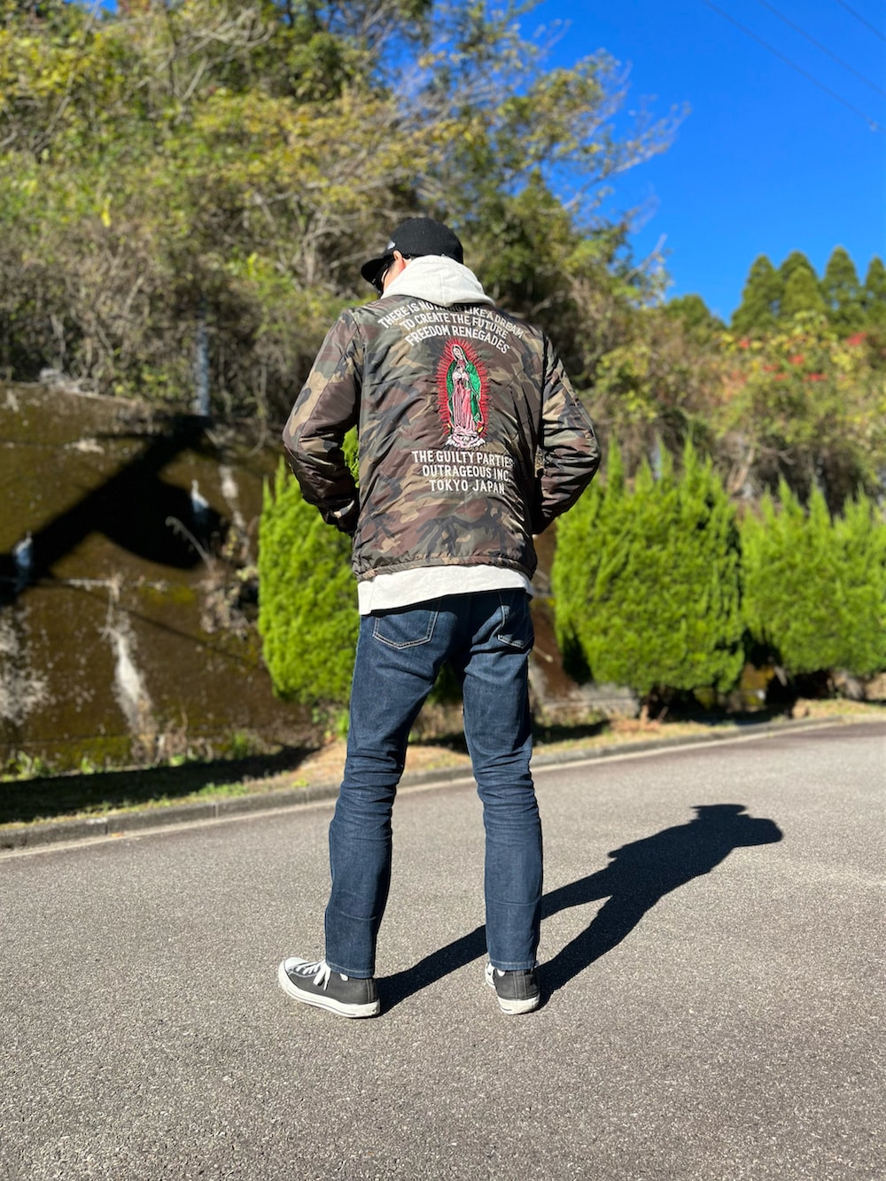 ホワイト系のパーカー、グリーン系のミリタリージャケット、ブルー系のデニムパンツを着用したメンズの冬コーディネートの3枚目の写真