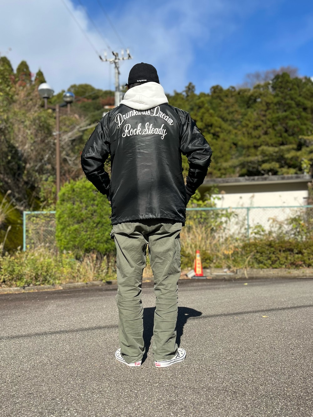 ホワイト系のパーカー、ブラック系のナイロンジャケット、グリーン系のパンツを着用したメンズの冬コーディネートの2枚目の写真