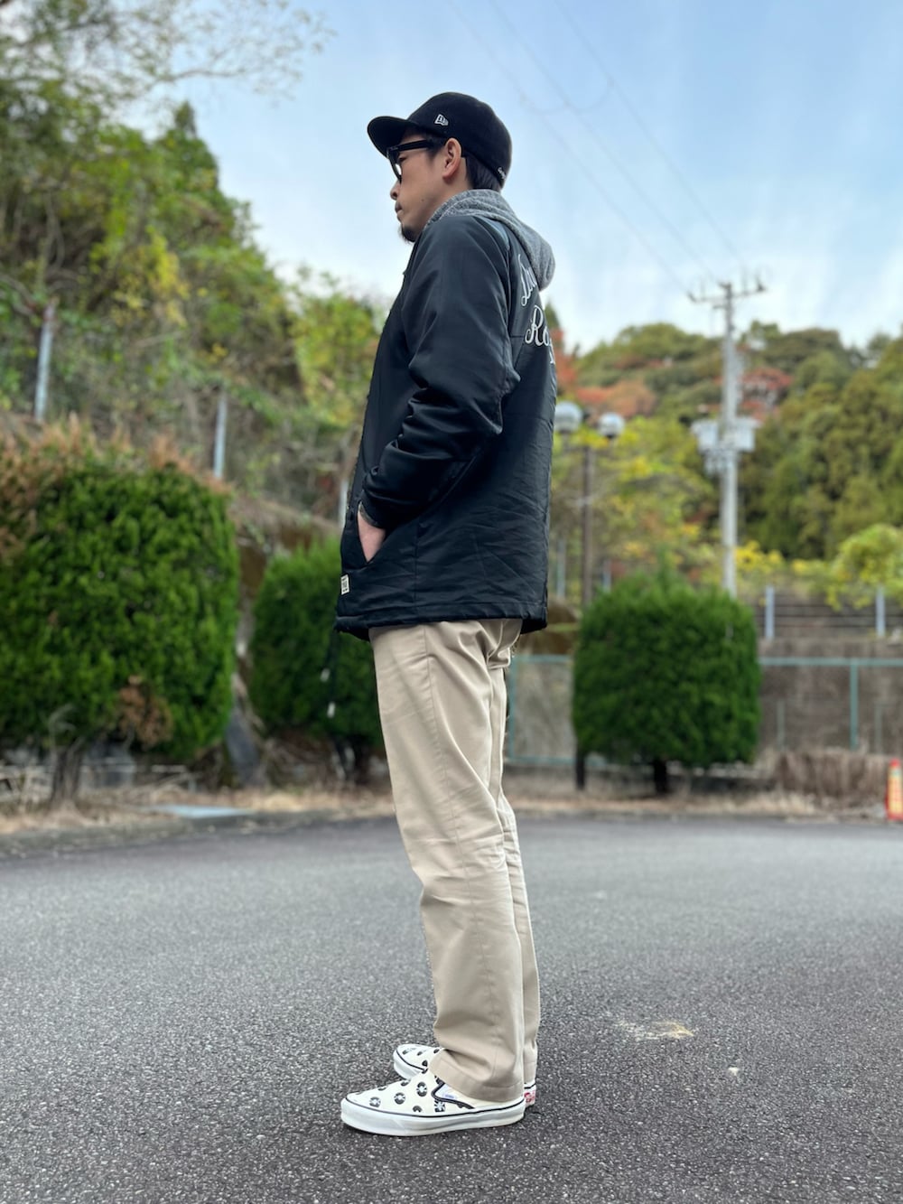 ブラック系のナイロンジャケット、ベージュ系のその他パンツ、ホワイト系のスリッポンを着用したメンズの秋コーディネートの2枚目の写真