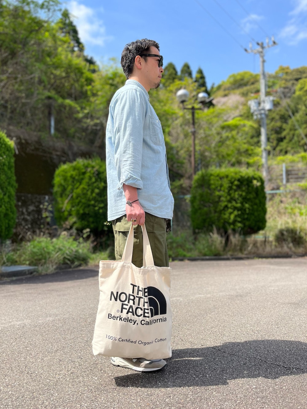 ブルー系のシャツ/ブラウス、ホワイト系のトートバッグ、グリーン系のカーゴパンツを着用したメンズの春コーディネートの2枚目の写真