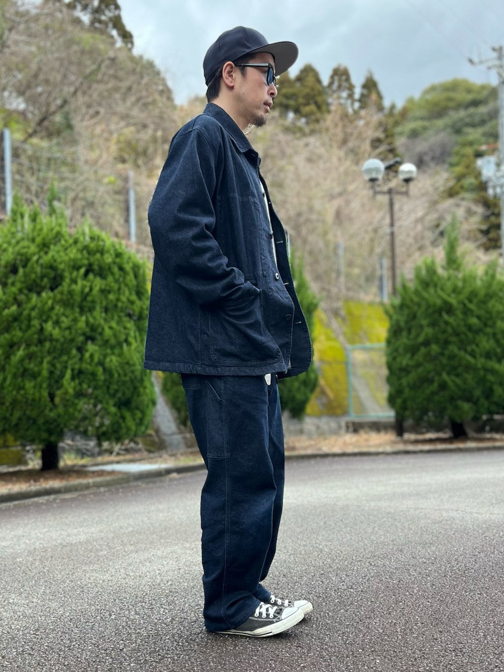 グレー系のスウェット、ブルー系のカバーオール、ブルー系のパンツを着用したメンズの春コーディネートの2枚目の写真