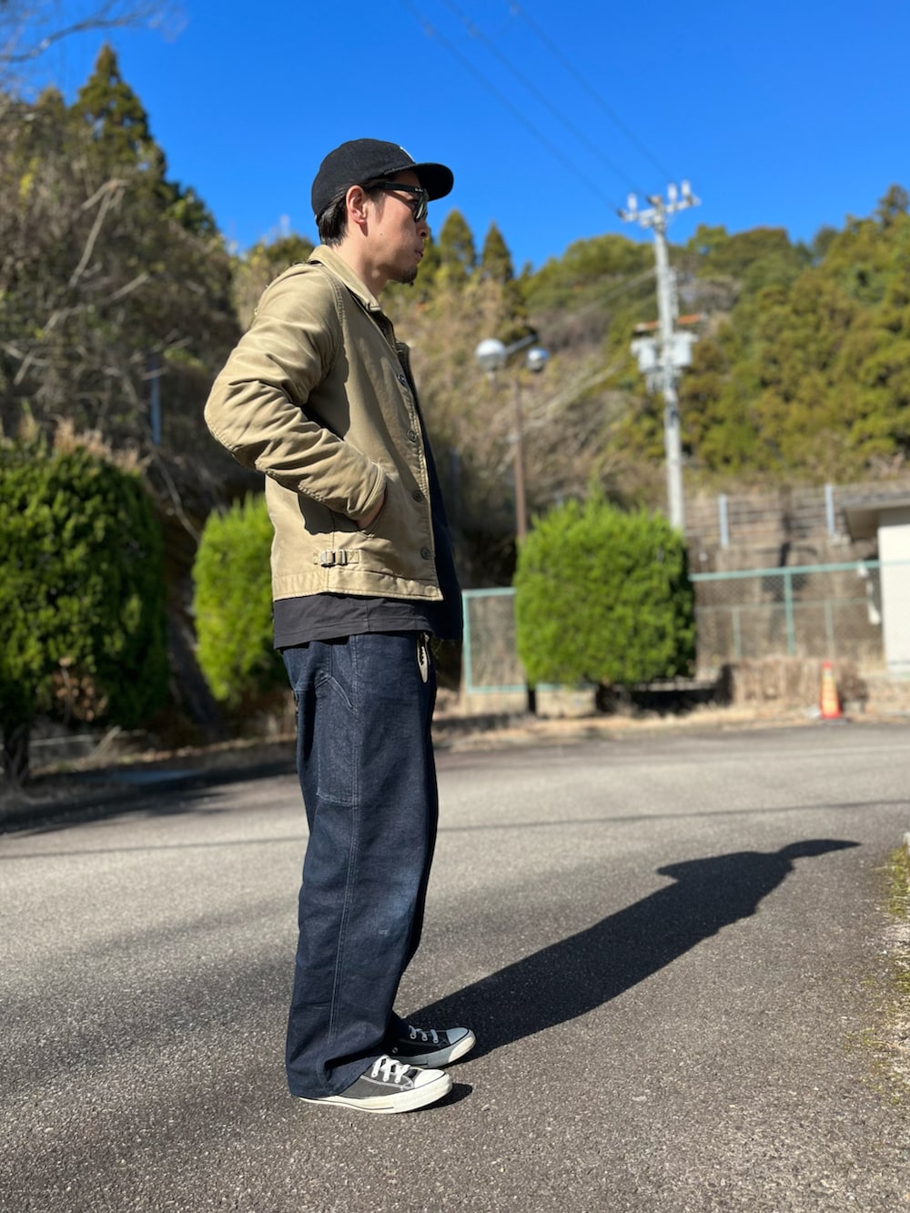 ホワイト系のTシャツ/カットソー、グリーン系のミリタリージャケット、ブルー系のパンツを着用したメンズの冬コーディネートの2枚目の写真