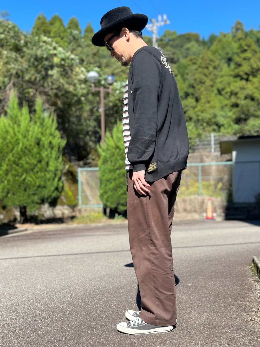 ブラック系のTシャツ/カットソー、ブラック系のカーディガン/ボレロ、ブラウン系のチノパンツを着用したメンズの秋コーディネートの4枚目の写真