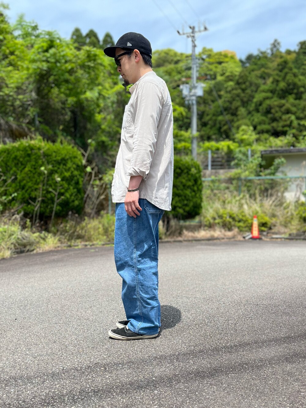 ホワイト系のタンクトップ、ブルー系のパンツ、ブラック系のスニーカーを着用したメンズの春コーディネートの2枚目の写真