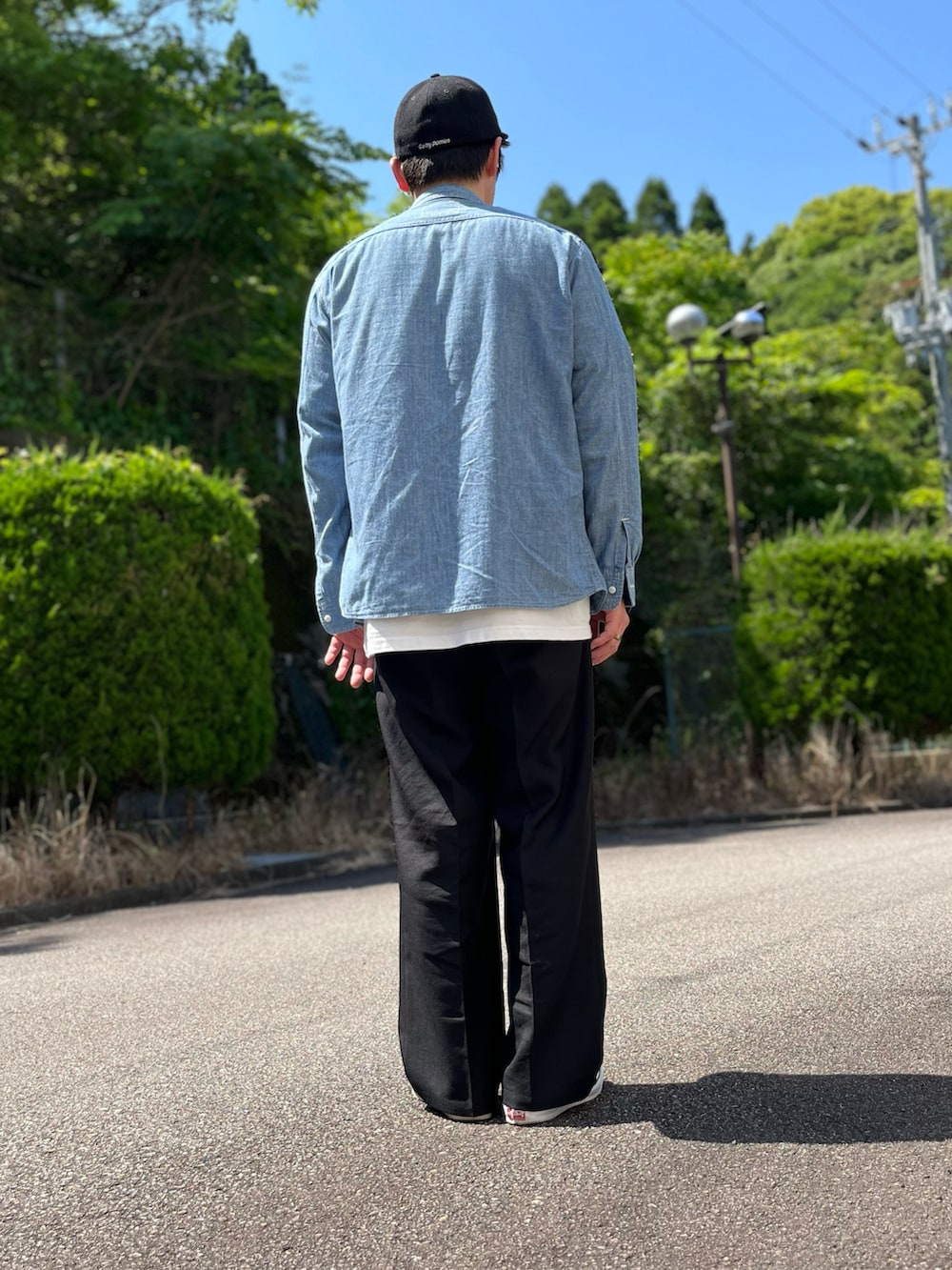 ホワイト系のTシャツ/カットソー、ブラック系のスラックス、ホワイト系のスリッポンを着用したメンズの春コーディネートの5枚目の写真