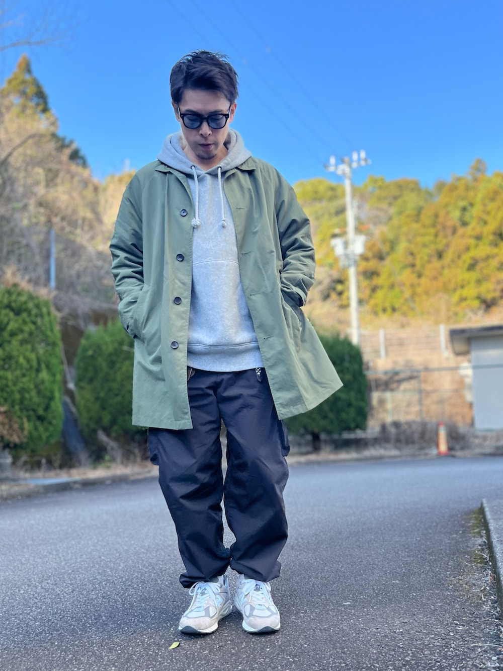 グレー系のパーカー、グリーン系のステンカラーコート、ブラック系のパンツを着用したメンズの冬コーディネートの5枚目の写真