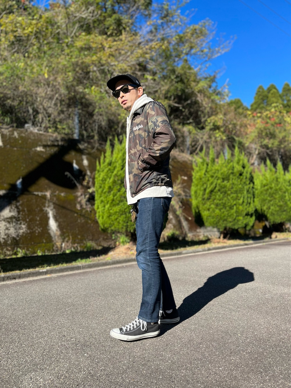 ホワイト系のパーカー、グリーン系のミリタリージャケット、ブルー系のデニムパンツを着用したメンズの冬コーディネートの2枚目の写真