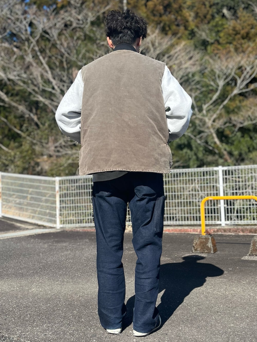 ブラウン系のダウンベスト、ブルー系のパンツ、ブラック系のスニーカーを着用したメンズの冬コーディネートの3枚目の写真
