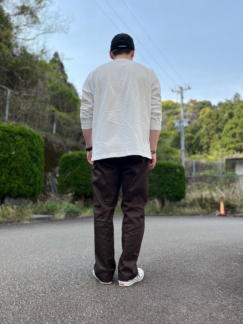 ホワイト系のTシャツ/カットソー、ブラウン系のチノパンツ、ホワイト系のスリッポンを着用したメンズの春コーディネートの4枚目の写真