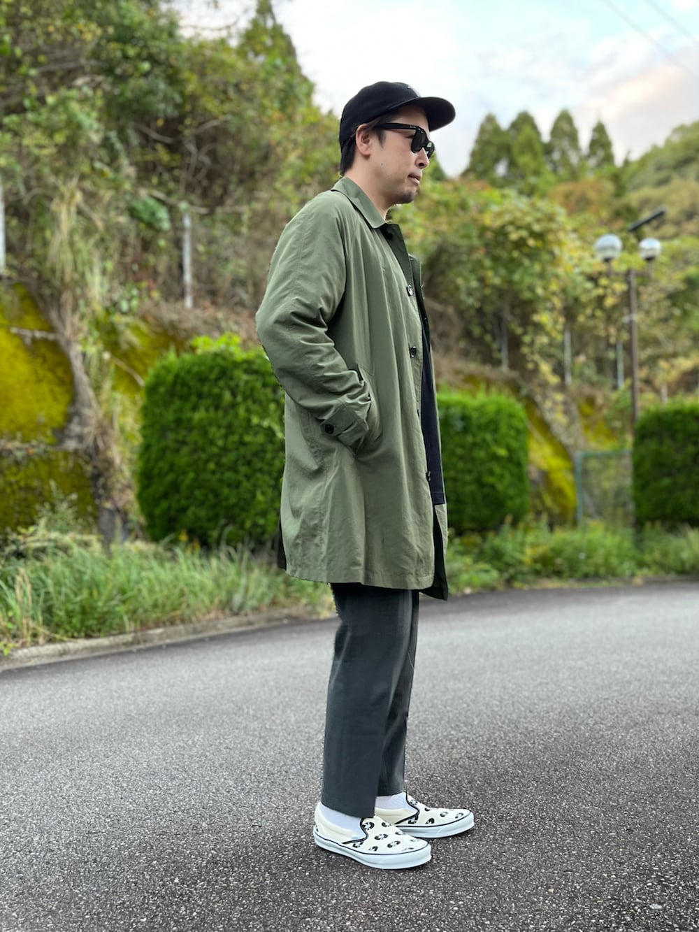 グリーン系のステンカラーコート、ホワイト系のTシャツ/カットソー、グレー系のその他パンツを着用したメンズの秋コーディネートの4枚目の写真