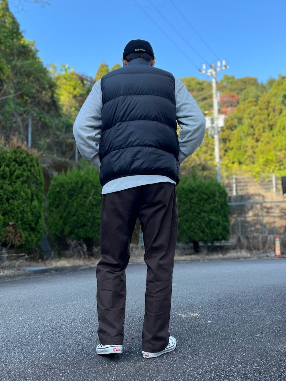 グレー系のスウェット、ブラック系のダウンベスト、ブラウン系のチノパンツを着用したメンズの秋コーディネートの3枚目の写真