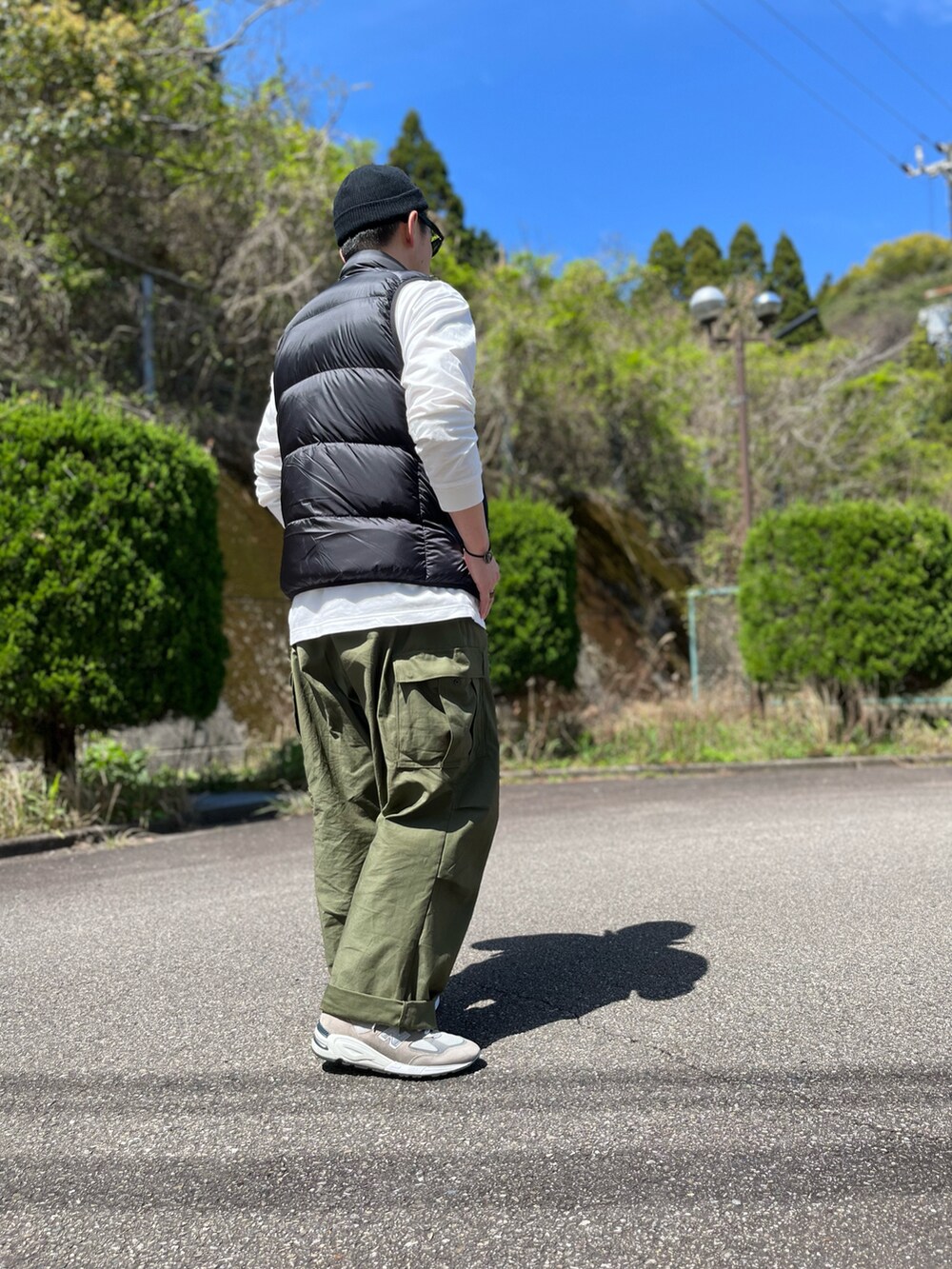 ブラック系のダウンベスト、ホワイト系のTシャツ/カットソー、グリーン系のカーゴパンツを着用したメンズの春コーディネートの3枚目の写真