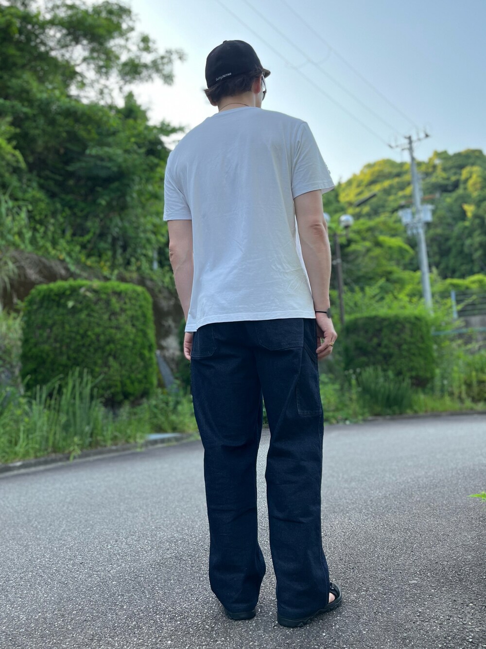 ホワイト系のTシャツ/カットソー、ブルー系のパンツ、ブラック系のサンダルを着用したメンズの夏コーディネートの2枚目の写真