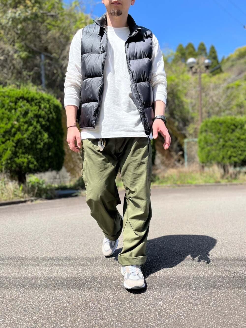 ブラック系のダウンベスト、ホワイト系のTシャツ/カットソー、グリーン系のカーゴパンツを着用したメンズの春コーディネートの5枚目の写真
