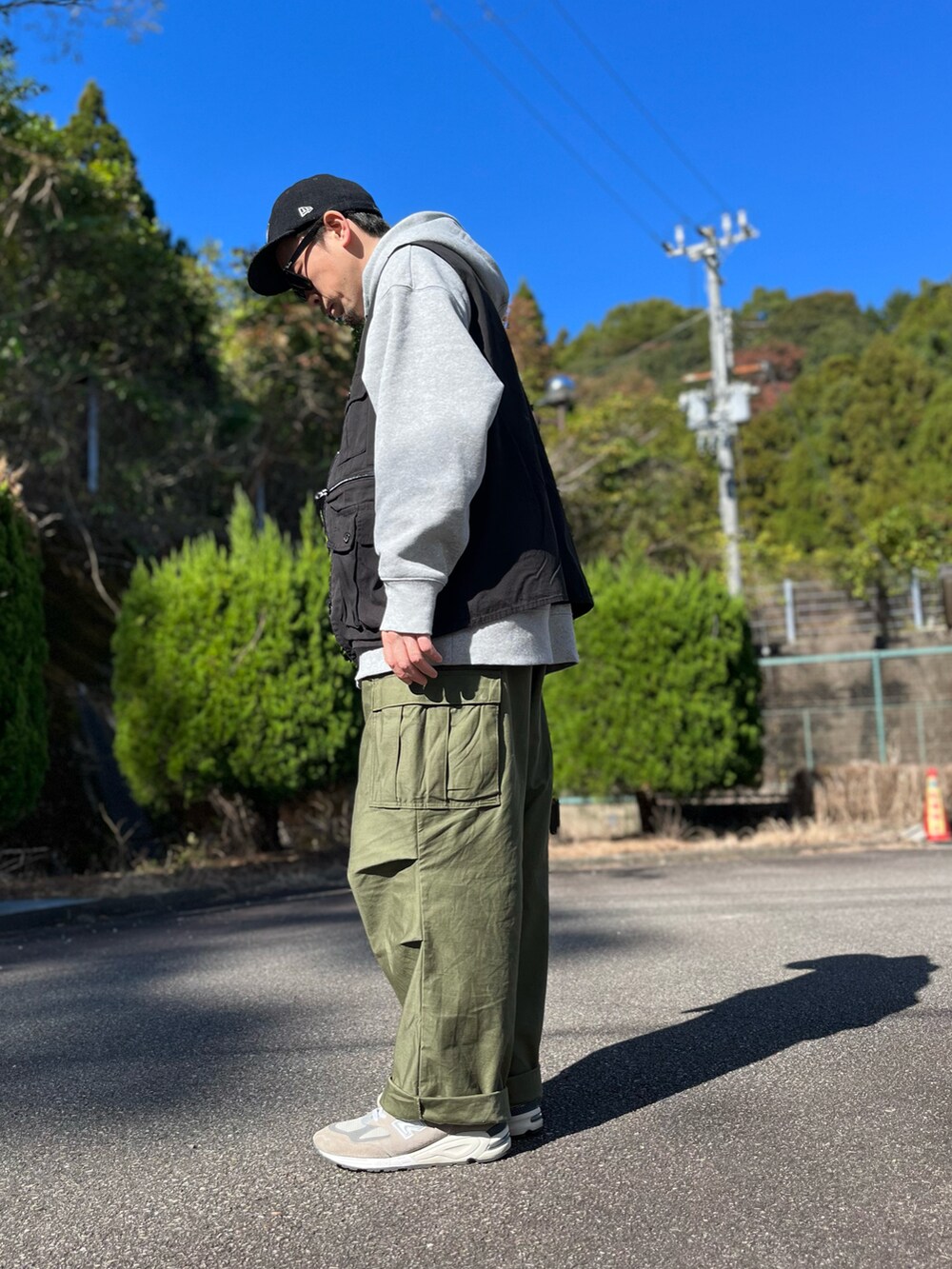 グレー系のパーカー、ブラック系のベスト、グリーン系のカーゴパンツを着用したメンズの秋コーディネートの2枚目の写真