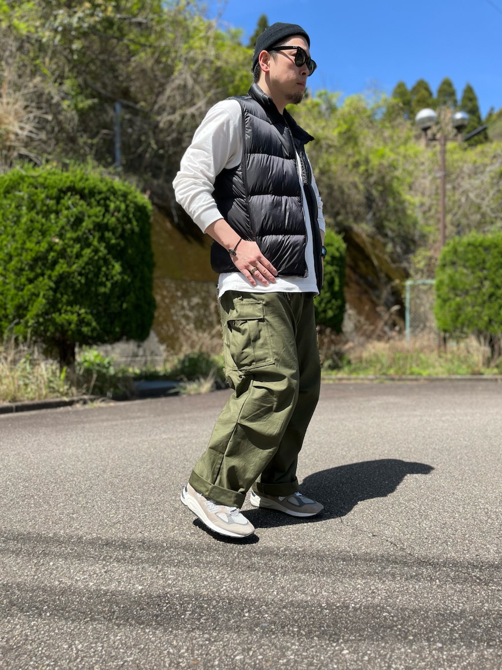 ブラック系のダウンベスト、ホワイト系のTシャツ/カットソー、グリーン系のカーゴパンツを着用したメンズの春コーディネートの2枚目の写真