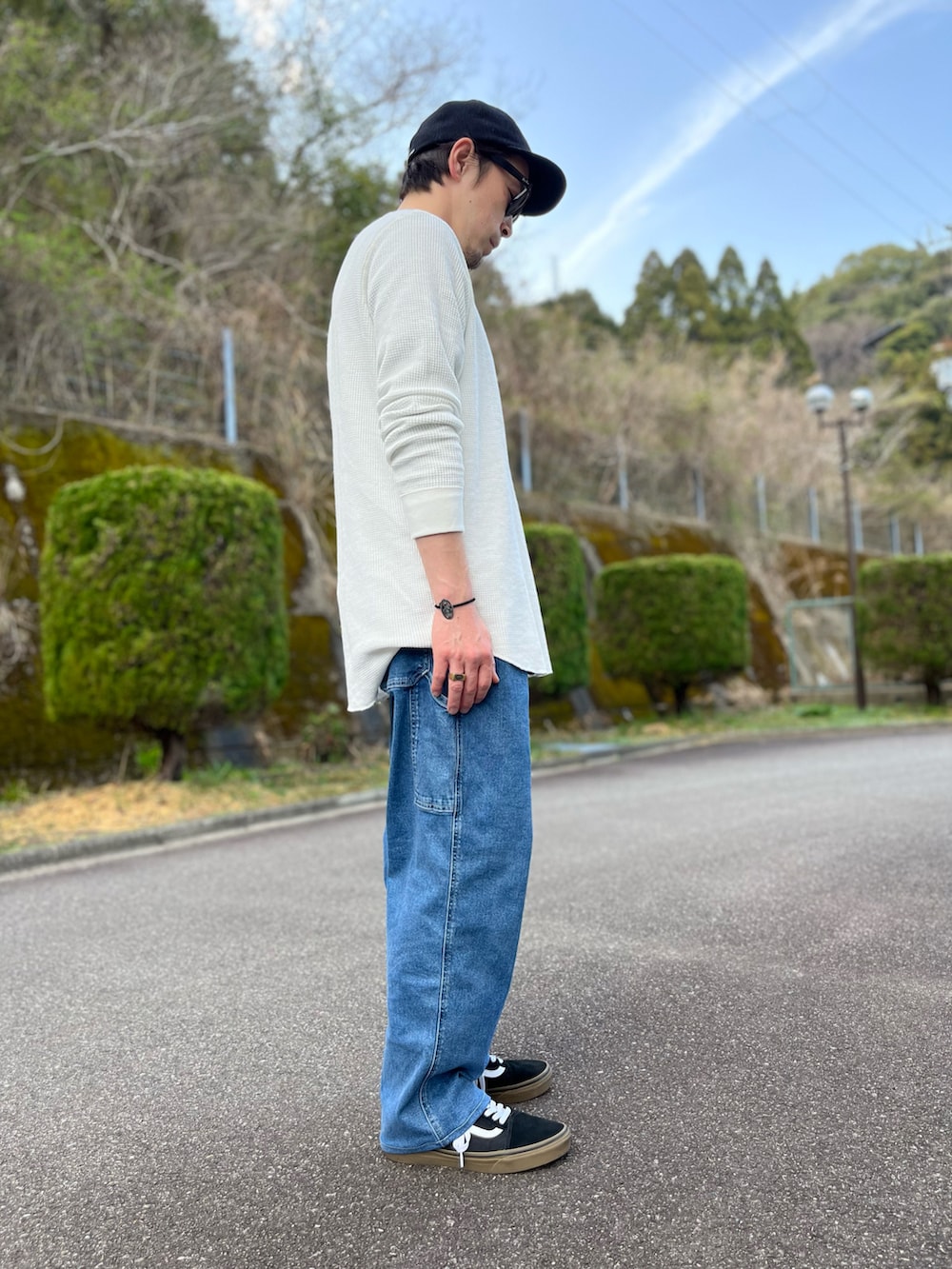 ホワイト系のTシャツ/カットソー、ブルー系のパンツ、ブラック系のスニーカーを着用したメンズの春コーディネートの2枚目の写真