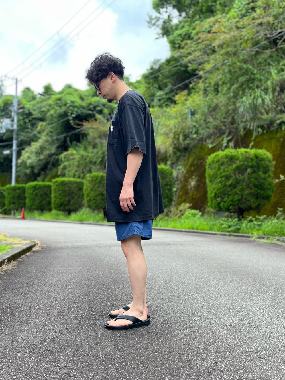 ブラック系のTシャツ/カットソー、ブルー系のパンツ、ブラック系のサンダルを着用したメンズの夏コーディネートの2枚目の写真