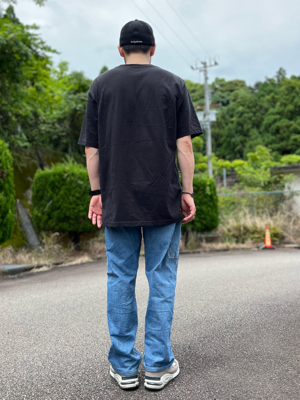 ブラック系のTシャツ/カットソー、ブルー系のパンツ、グレー系のスニーカーを着用したメンズの夏コーディネートの3枚目の写真