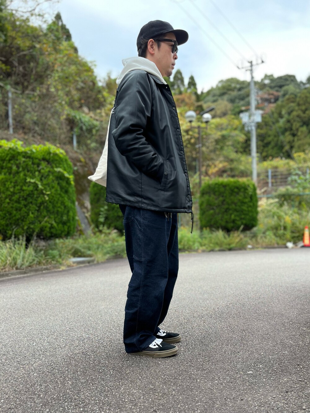 ホワイト系のパーカー、ホワイト系のトートバッグ、ブラック系のナイロンジャケットを着用したメンズの秋コーディネートの4枚目の写真