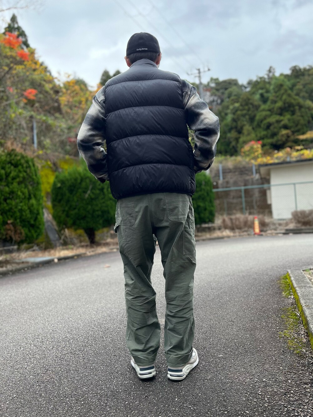 ブラック系のダウンベスト、ブラック系のトップス、グリーン系のパンツを着用したメンズの冬コーディネートの3枚目の写真