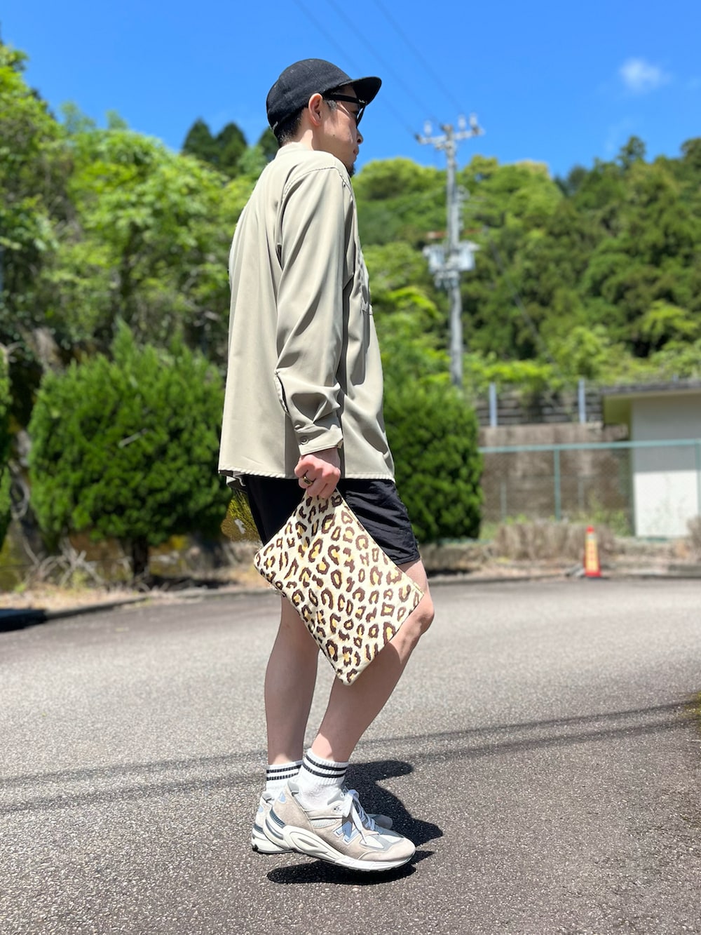 ブラック系のその他パンツ、その他のクラッチバッグ、グレー系のスニーカーを着用したメンズの春コーディネートの2枚目の写真