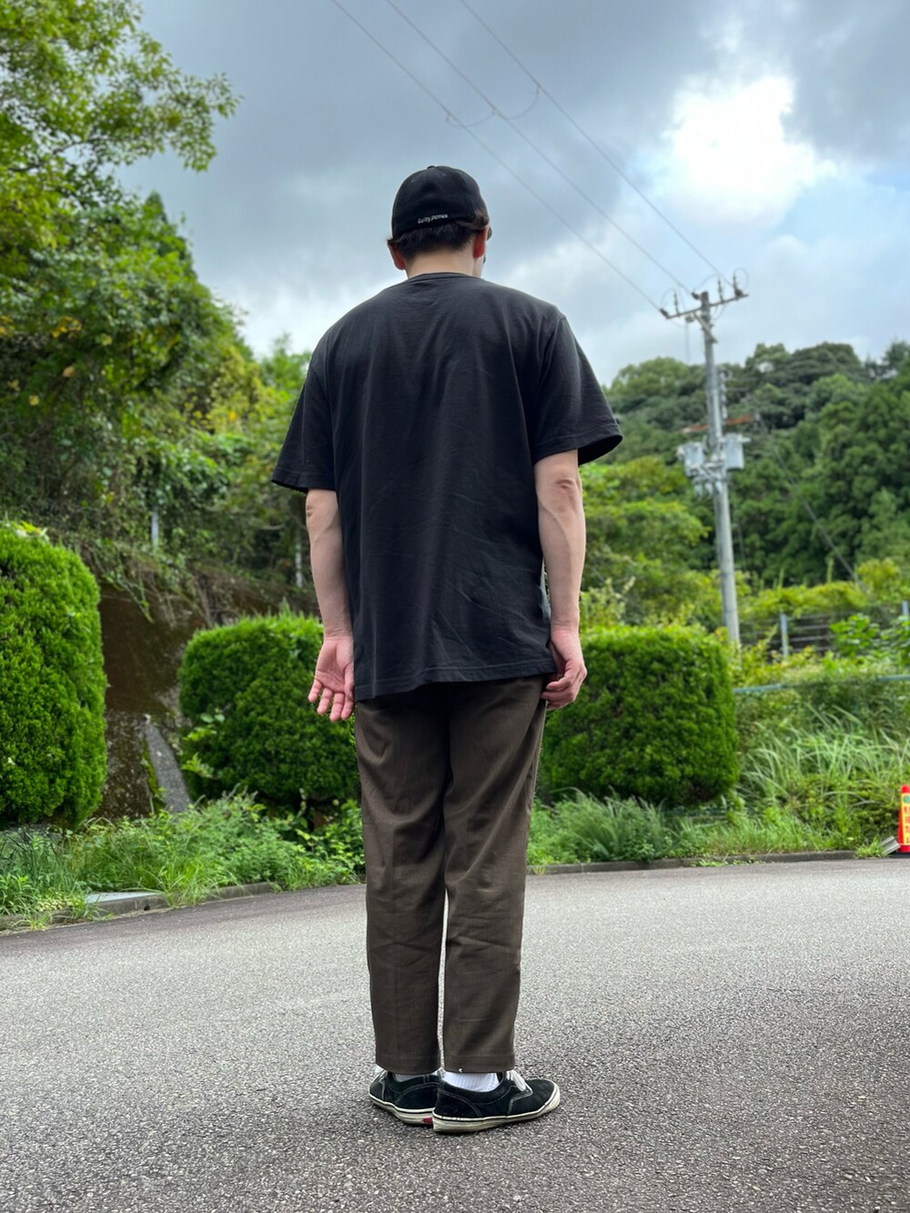 ブラック系のTシャツ/カットソー、ブラウン系のスラックス、ブラック系のスニーカーを着用したメンズの秋コーディネートの3枚目の写真