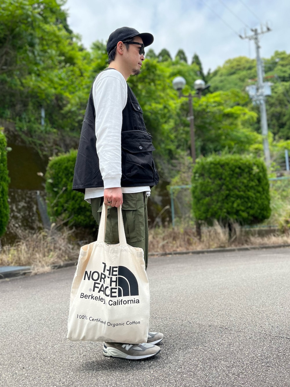 ホワイト系のTシャツ/カットソー、ブラック系のベスト、グリーン系のカーゴパンツを着用したメンズの春コーディネートの2枚目の写真