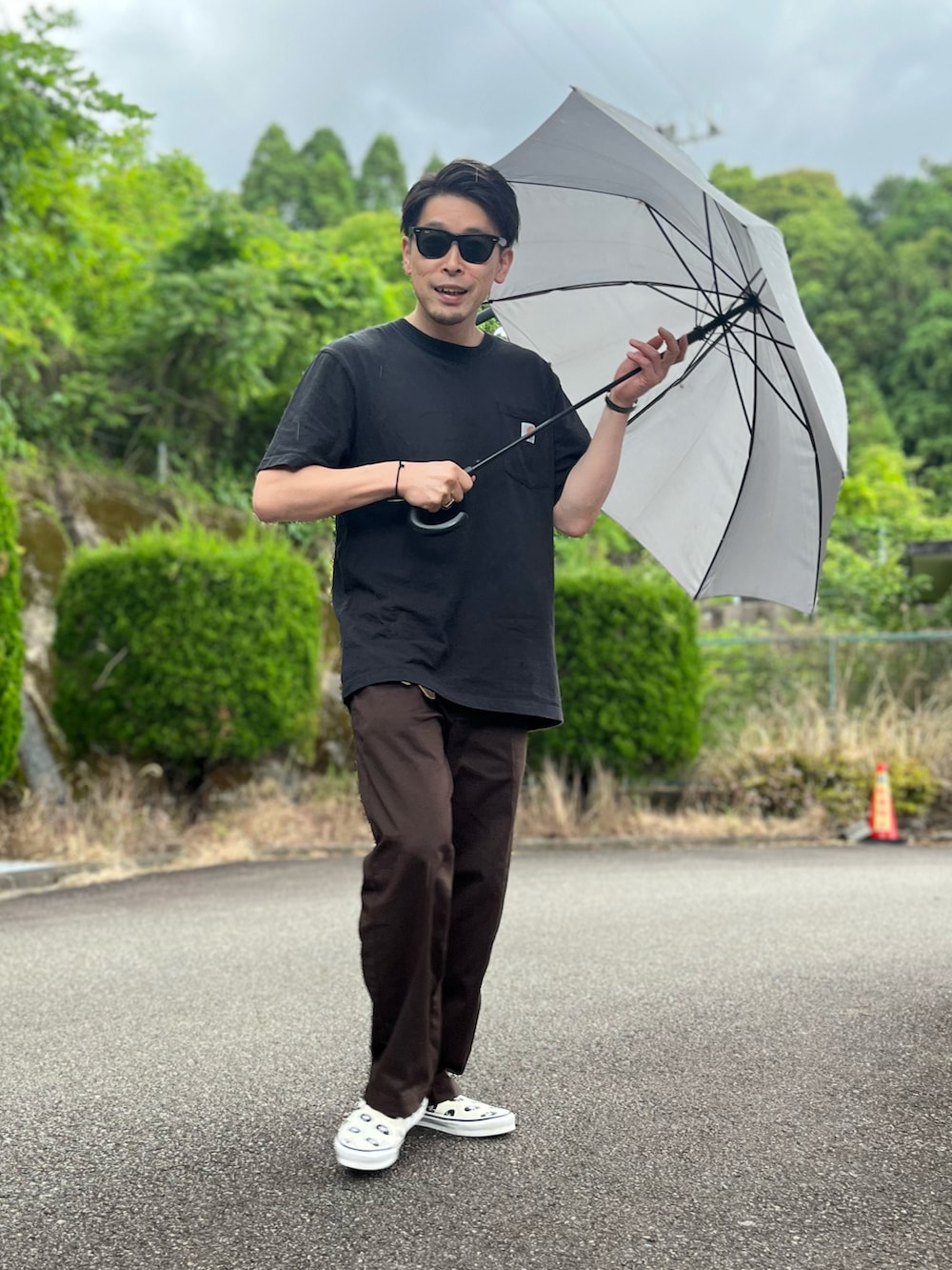 ブラック系のTシャツ/カットソー、ブラウン系のチノパンツ、ホワイト系のスリッポンを着用したメンズの春コーディネートの4枚目の写真
