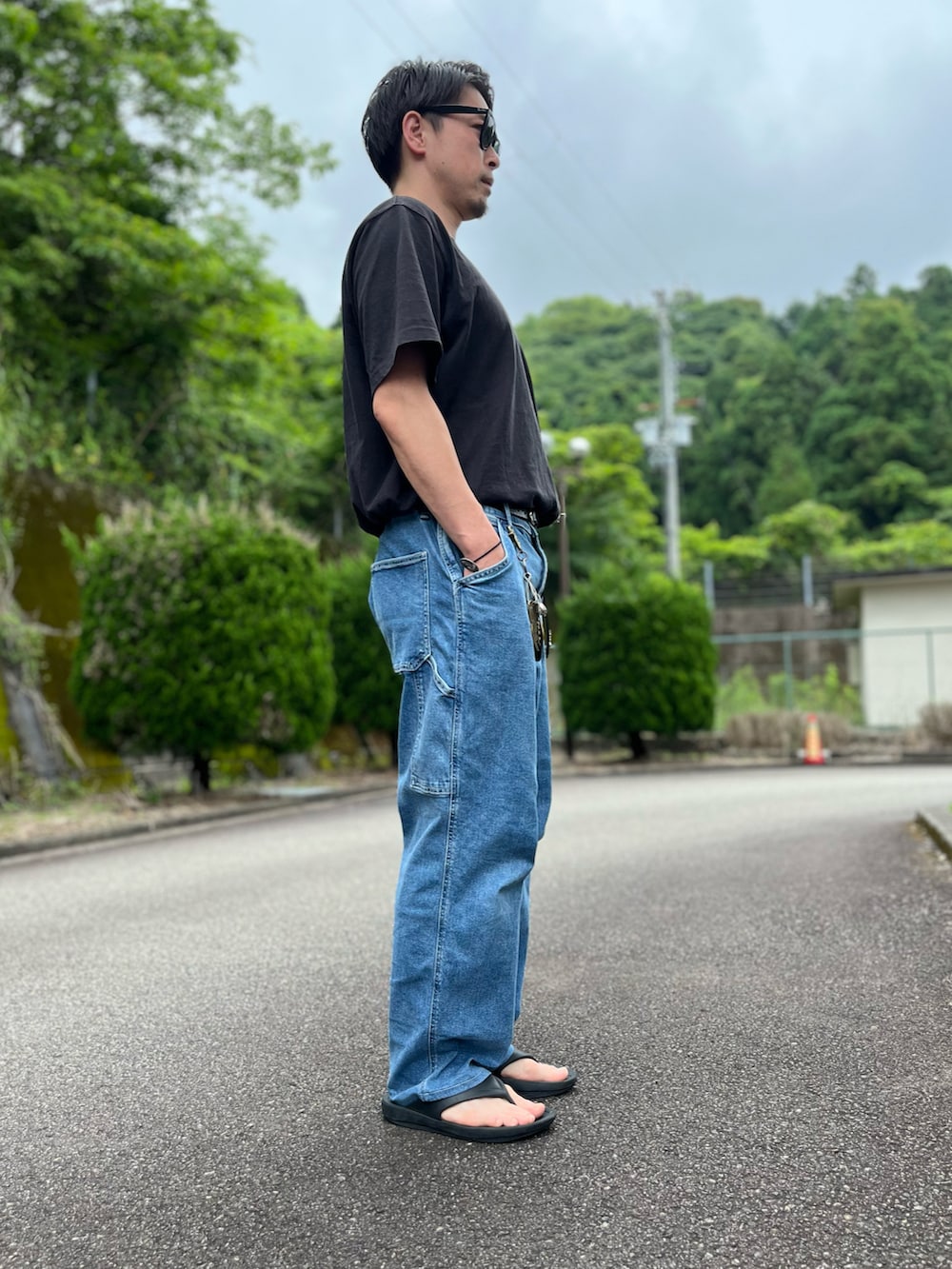 ブラック系のTシャツ/カットソー、ブルー系のパンツ、ブラック系のサンダルを着用したメンズの夏コーディネートの2枚目の写真