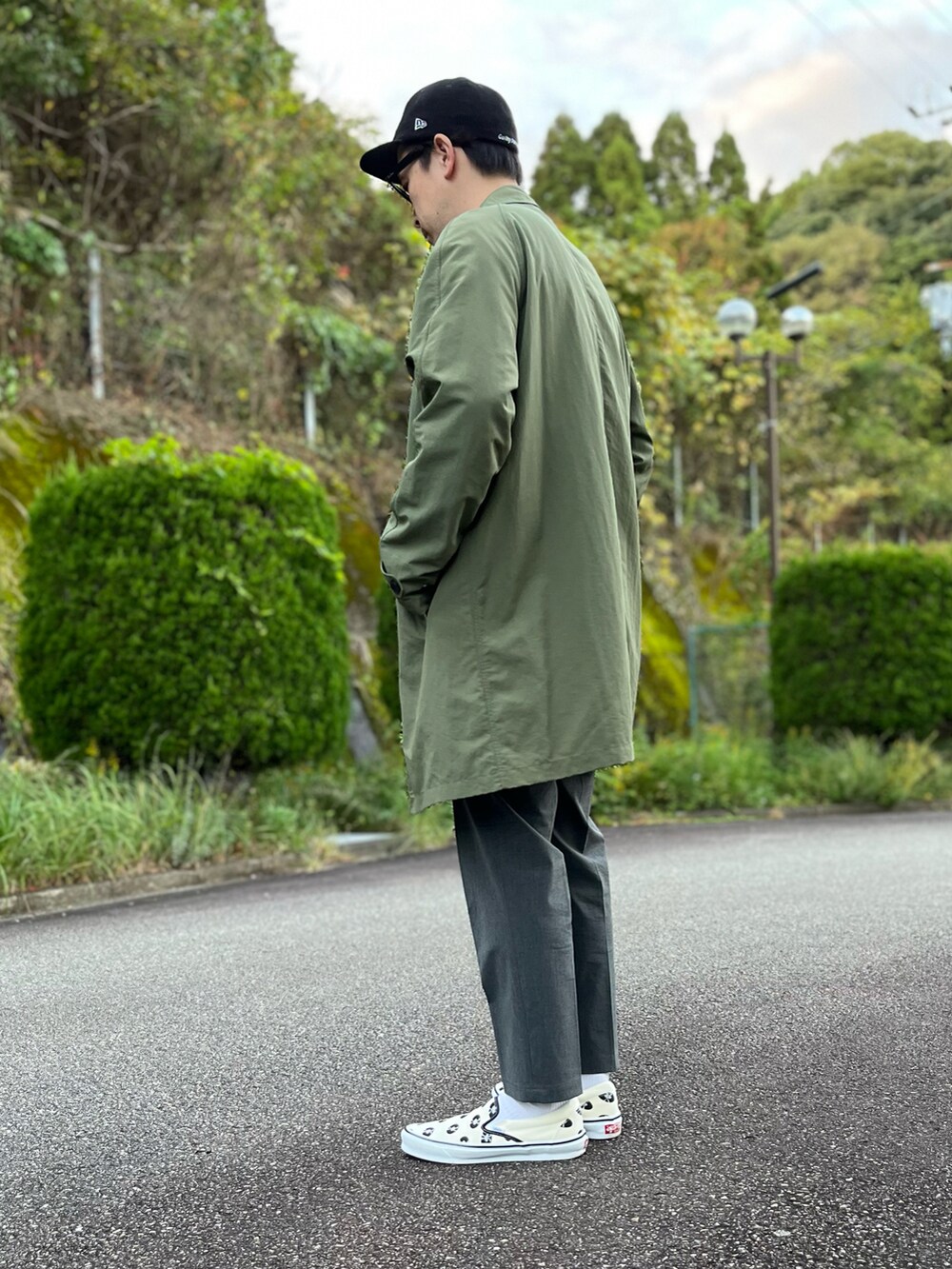 グリーン系のステンカラーコート、ホワイト系のTシャツ/カットソー、グレー系のその他パンツを着用したメンズの秋コーディネートの3枚目の写真