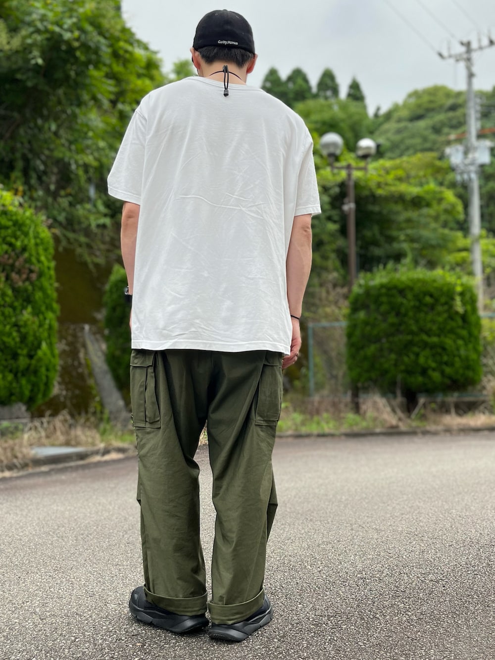 ホワイト系のTシャツ/カットソー、グリーン系のカーゴパンツ、ブラック系のスニーカーを着用したメンズの夏コーディネートの3枚目の写真