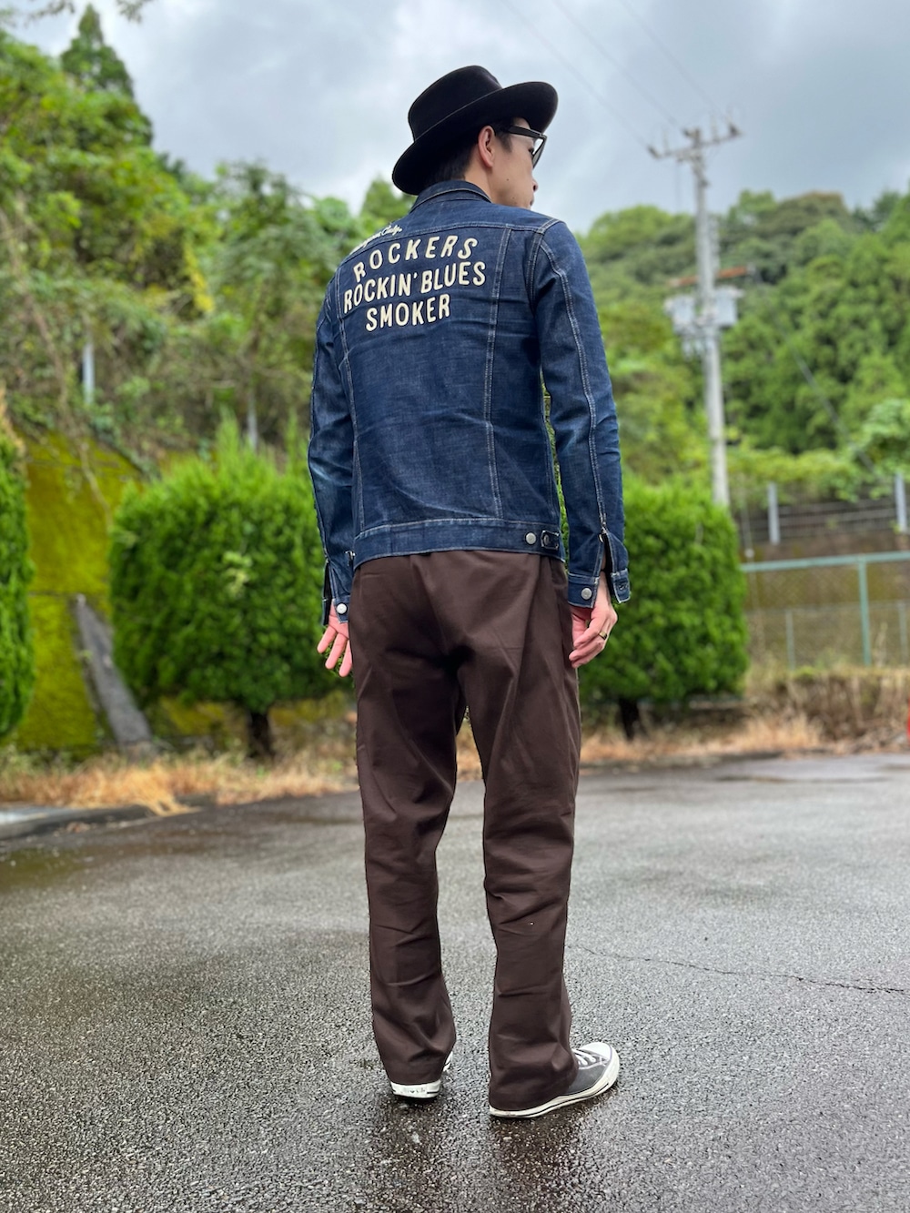 ブルー系のデニムジャケット、ブラウン系のチノパンツ、ブラック系のスニーカーを着用したメンズの秋コーディネートの3枚目の写真