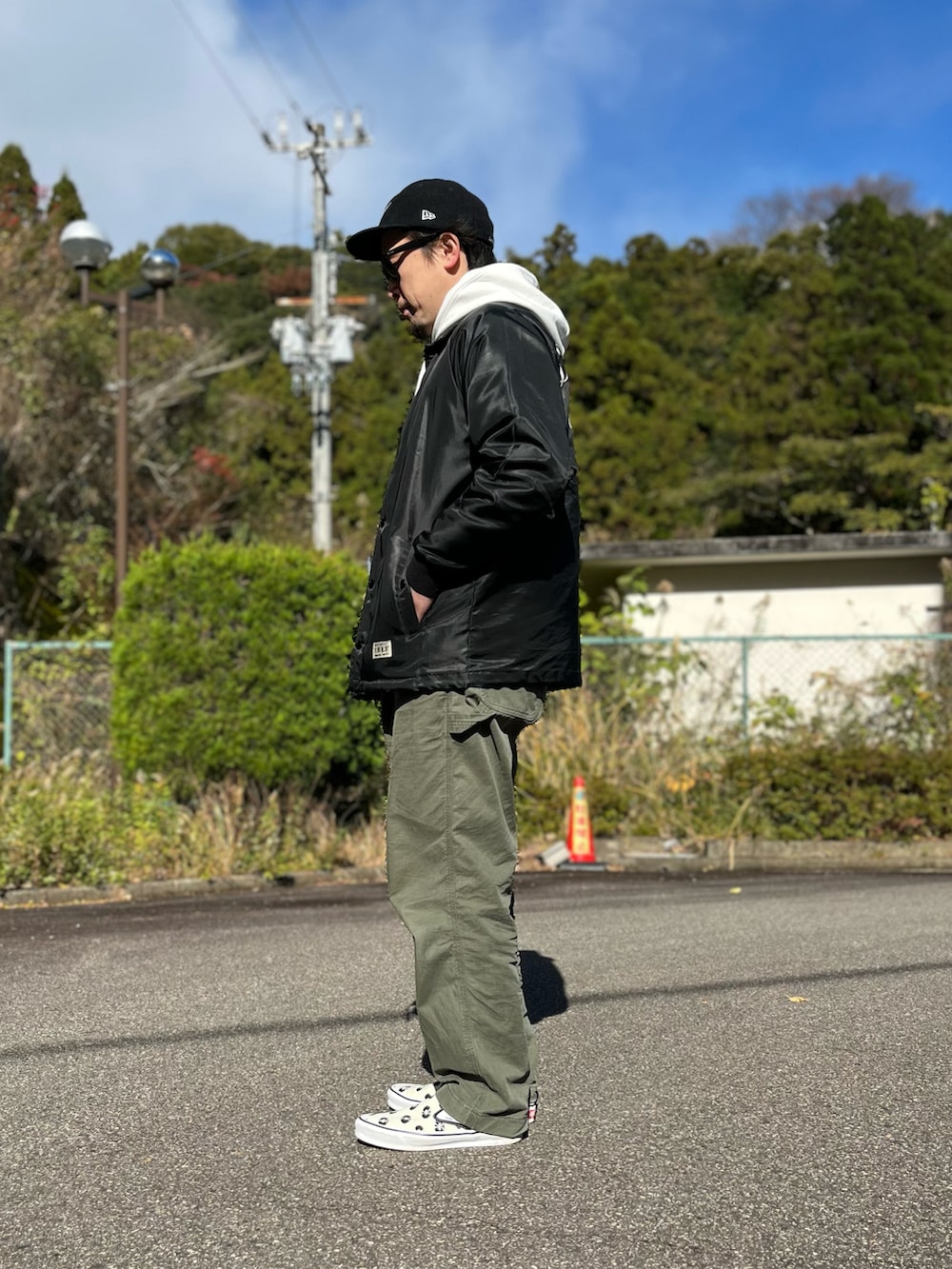 ホワイト系のパーカー、ブラック系のナイロンジャケット、グリーン系のパンツを着用したメンズの冬コーディネートの3枚目の写真