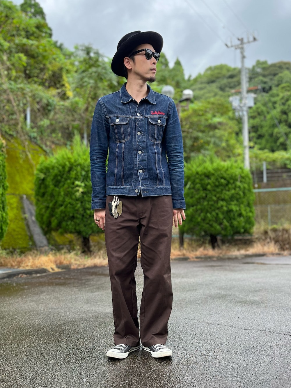 ブルー系のデニムジャケット、ブラウン系のチノパンツ、ブラック系のスニーカーを着用したメンズの秋コーディネートの5枚目の写真