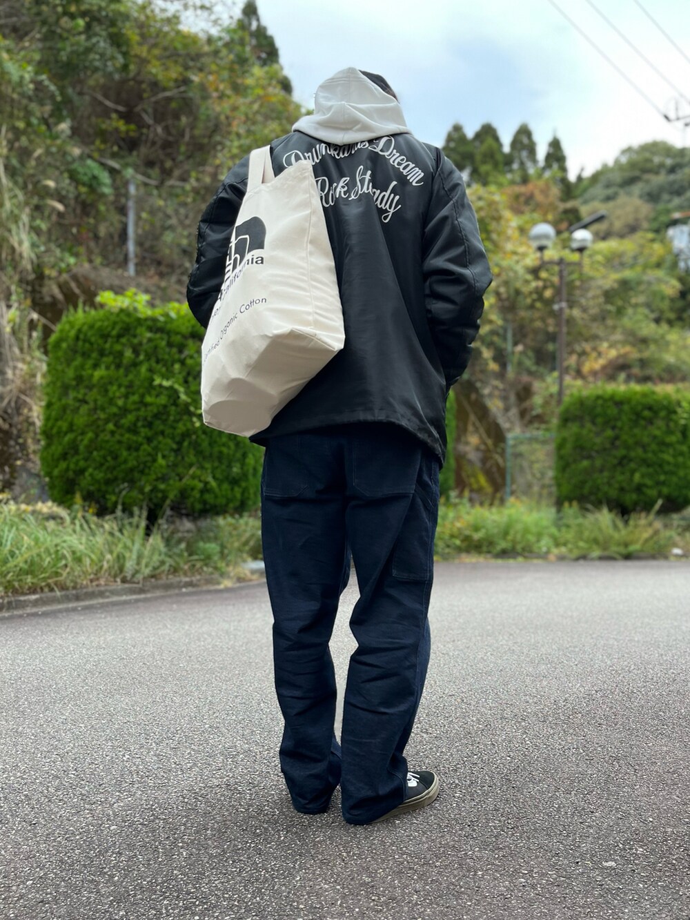 ホワイト系のパーカー、ホワイト系のトートバッグ、ブラック系のナイロンジャケットを着用したメンズの秋コーディネートの3枚目の写真