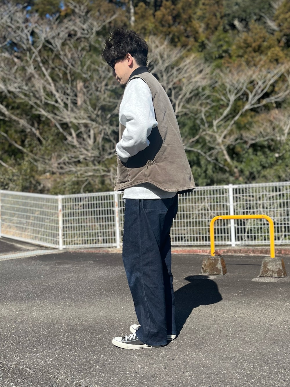 ブラウン系のダウンベスト、ブルー系のパンツ、ブラック系のスニーカーを着用したメンズの冬コーディネートの4枚目の写真
