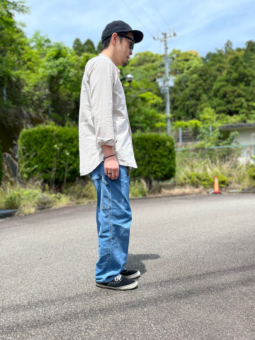 ホワイト系のタンクトップ、ブルー系のパンツ、ブラック系のスニーカーを着用したメンズの春コーディネートの4枚目の写真