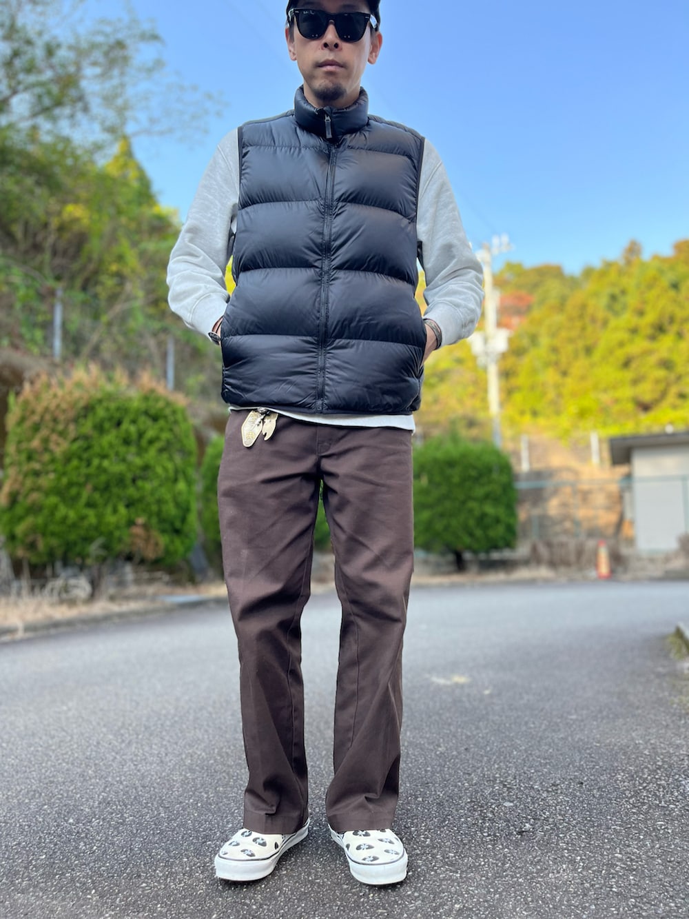 グレー系のスウェット、ブラック系のダウンベスト、ブラウン系のチノパンツを着用したメンズの秋コーディネートの5枚目の写真