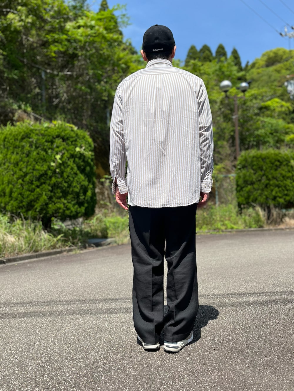 ホワイト系のTシャツ/カットソー、ブラウン系のシャツ/ブラウス、ブラック系のスラックスを着用したメンズの春コーディネートの3枚目の写真
