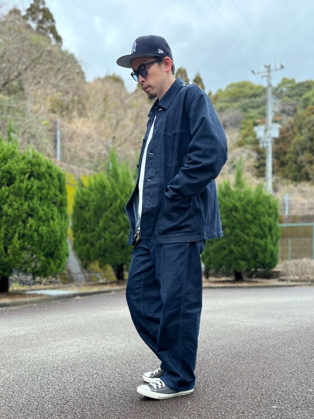 グレー系のスウェット、ブルー系のカバーオール、ブルー系のパンツを着用したメンズの春コーディネートの4枚目の写真
