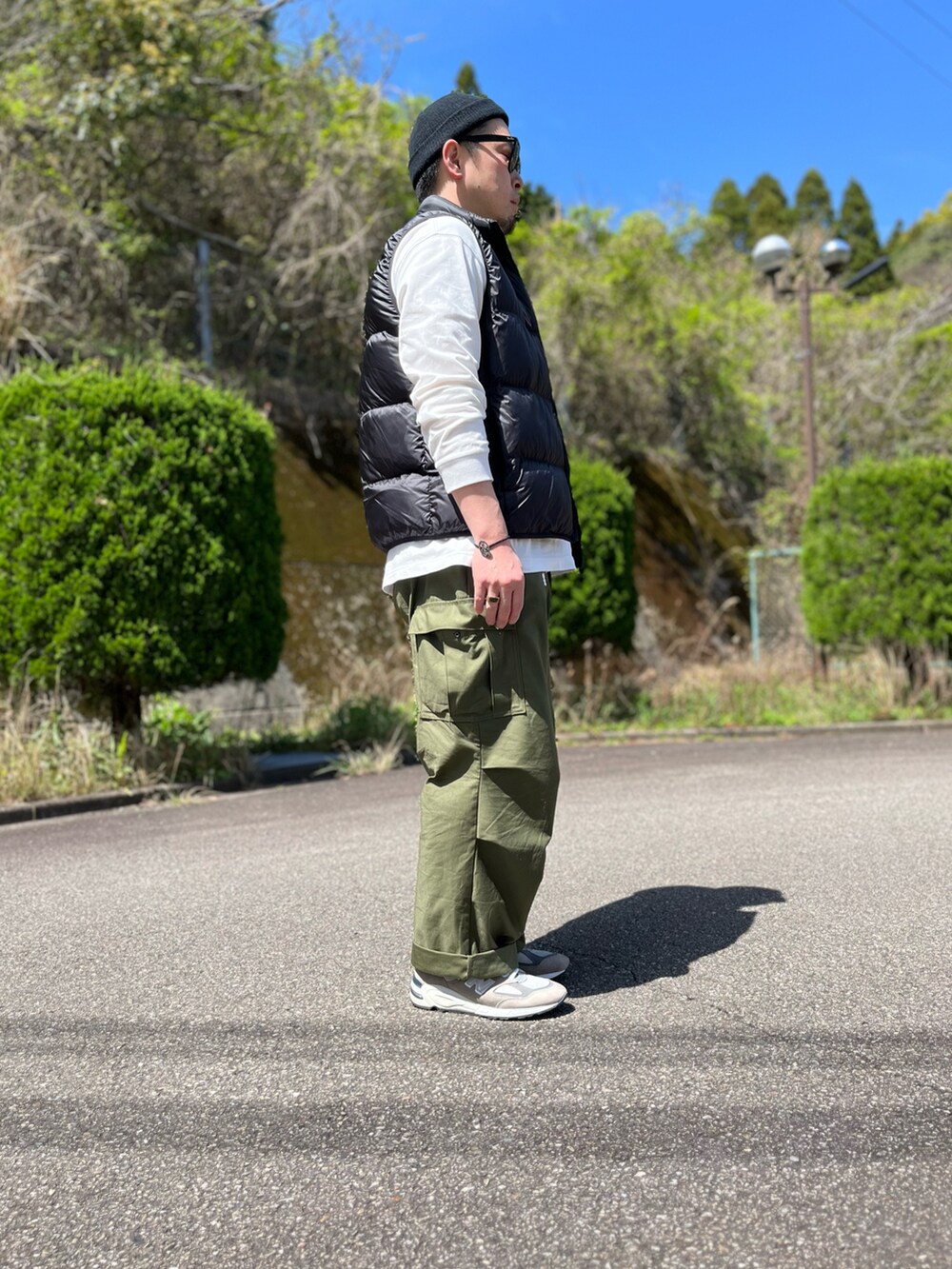 ブラック系のダウンベスト、ホワイト系のTシャツ/カットソー、グリーン系のカーゴパンツを着用したメンズの春コーディネートの4枚目の写真