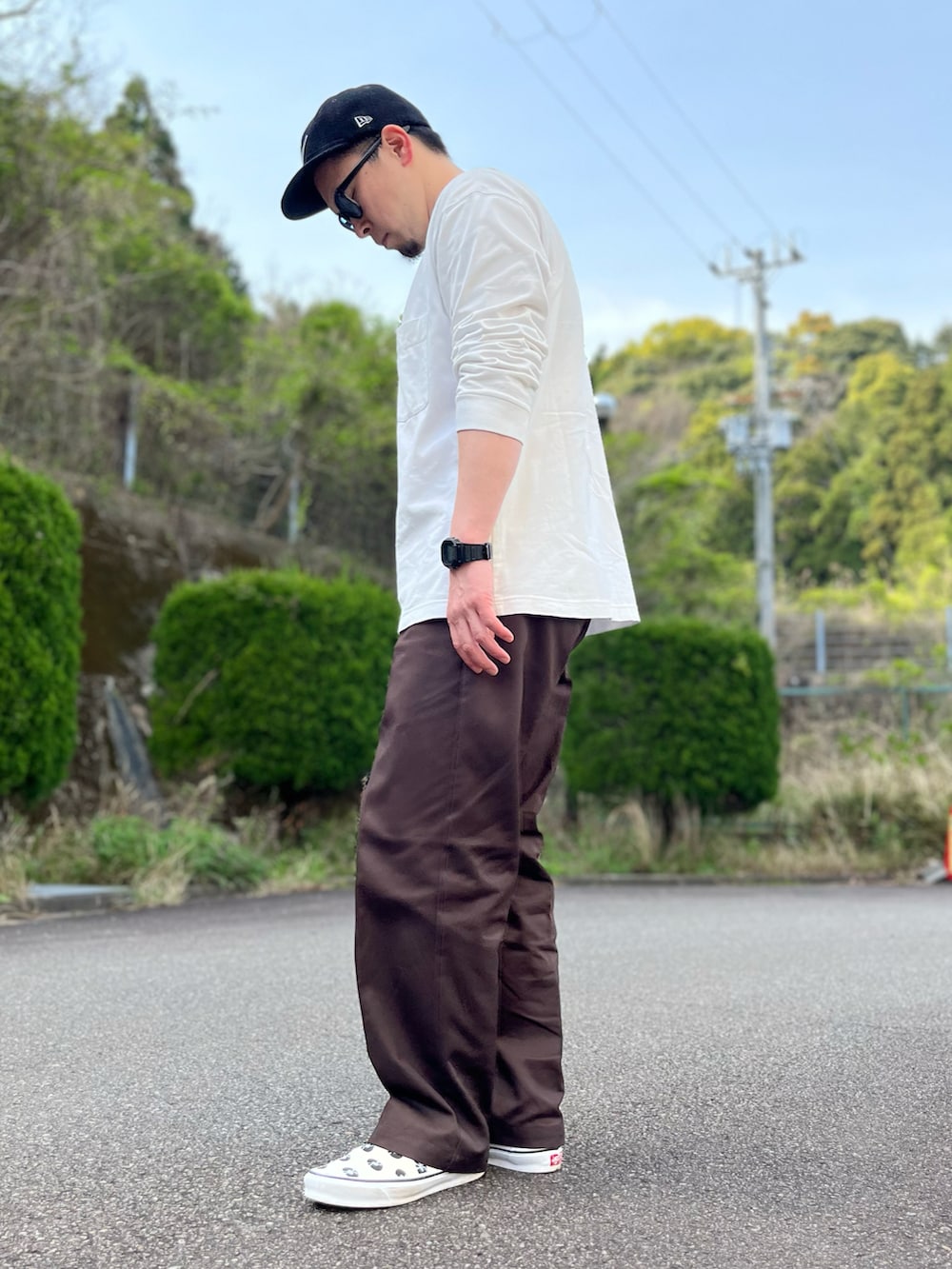 ホワイト系のTシャツ/カットソー、ブラウン系のチノパンツ、ホワイト系のスリッポンを着用したメンズの春コーディネートの2枚目の写真
