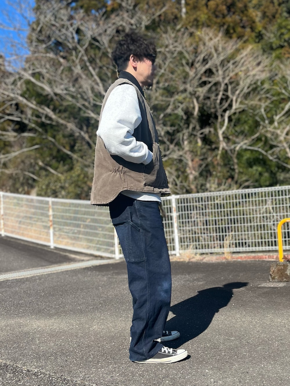 ブラウン系のダウンベスト、ブルー系のパンツ、ブラック系のスニーカーを着用したメンズの冬コーディネートの2枚目の写真