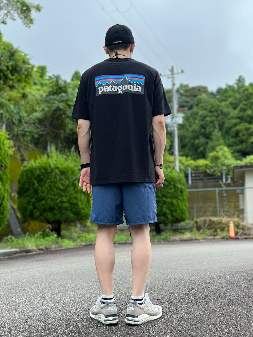 ブラック系のTシャツ/カットソー、ブルー系のパンツ、グレー系のスニーカーを着用したメンズの夏コーディネートの3枚目の写真
