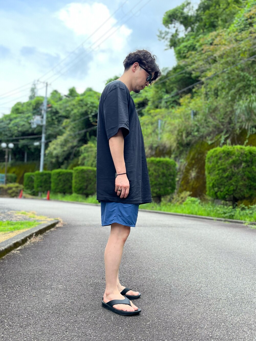 ブラック系のTシャツ/カットソー、ブルー系のパンツ、ブラック系のサンダルを着用したメンズの夏コーディネートの4枚目の写真