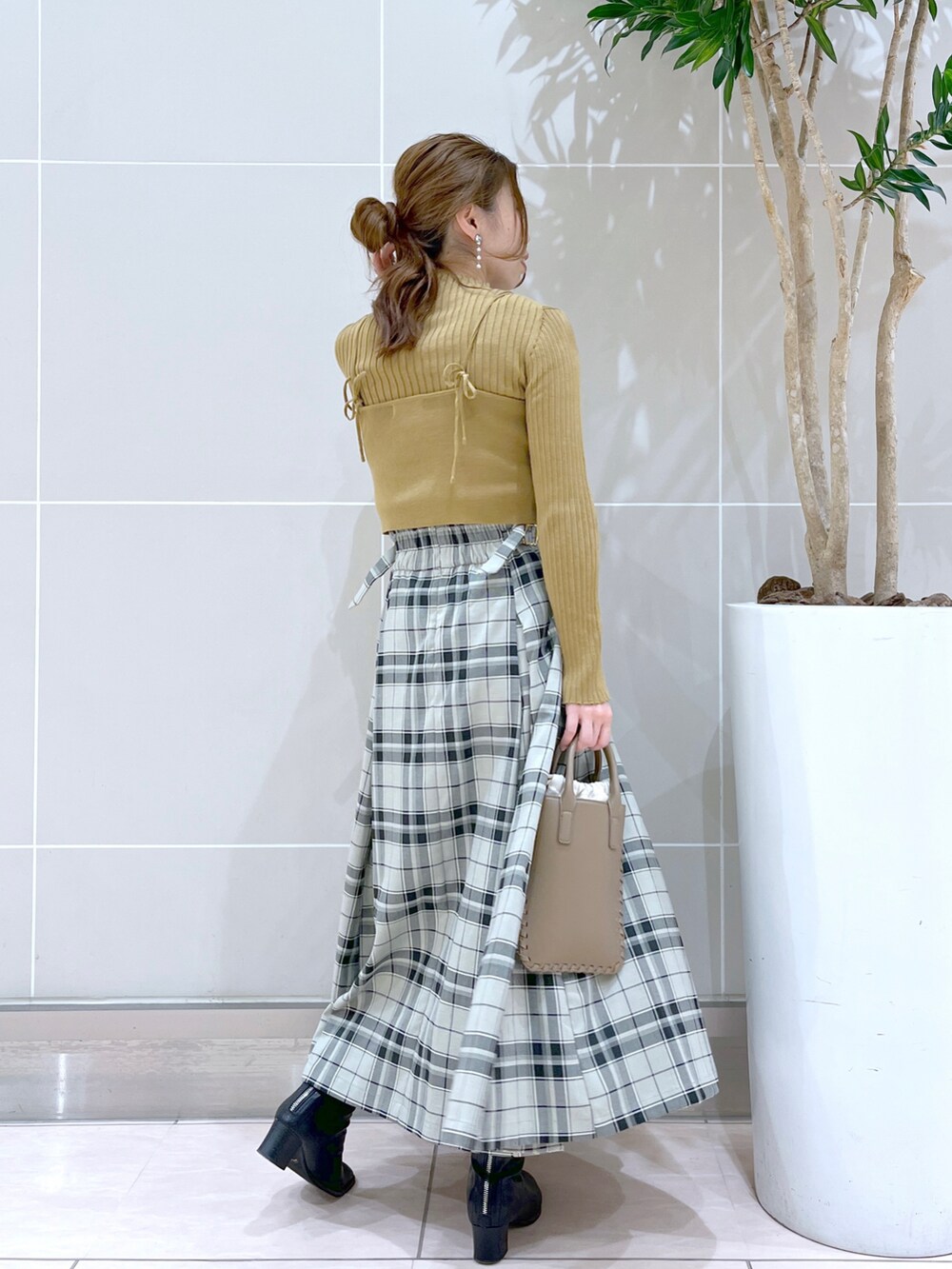 グリーン系のスカート、ブラック系のブーツ、ブラウン系のショルダーバッグを着用したレディースの秋コーディネートの2枚目の写真