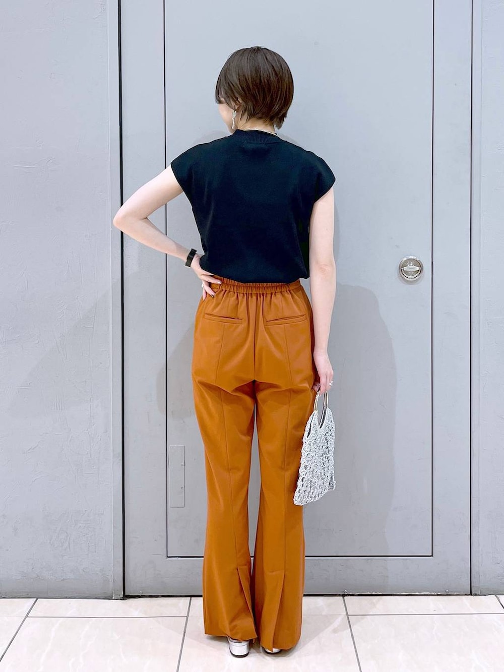 ブラック系のニット/セーター、シルバー系のハンドバッグ、シルバー系のサンダルを着用したレディースの夏コーディネートの4枚目の写真